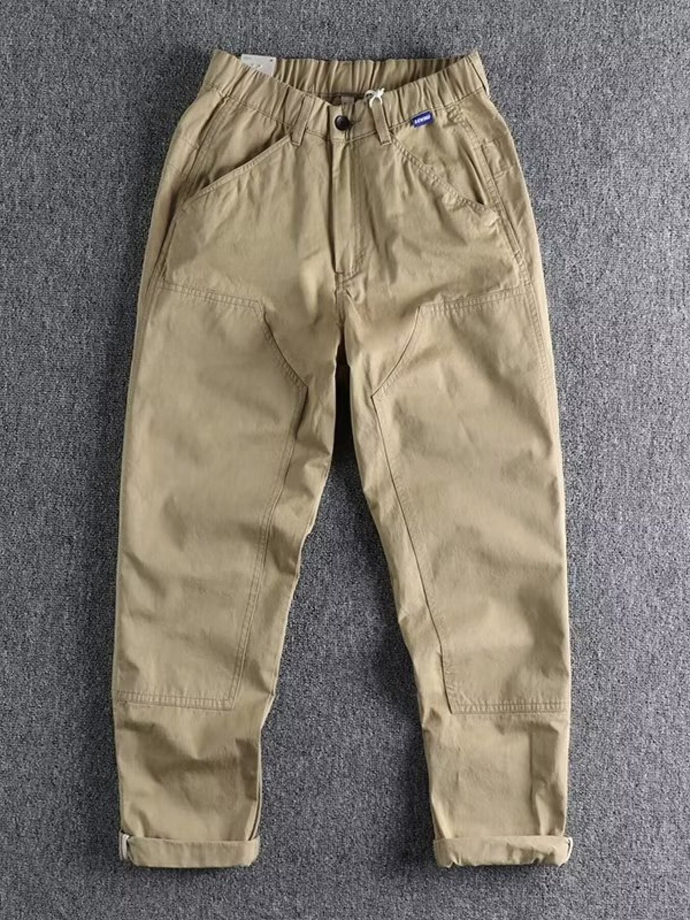 Khaki men's elastic waist cargo pants with button closure and cuffed hems.
