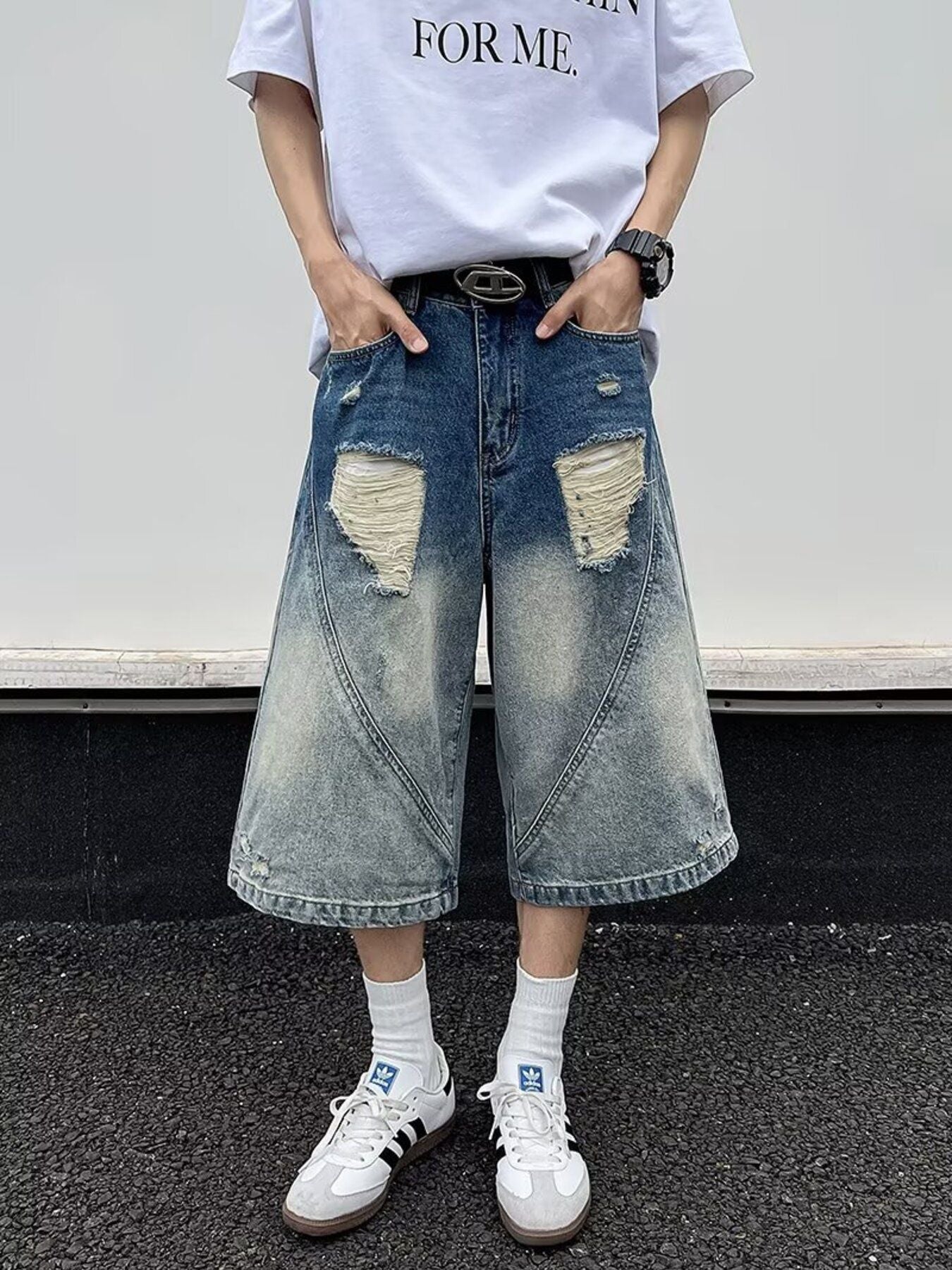 Men's distressed wide-leg denim shorts in blue with ripped details and a faded wash.
