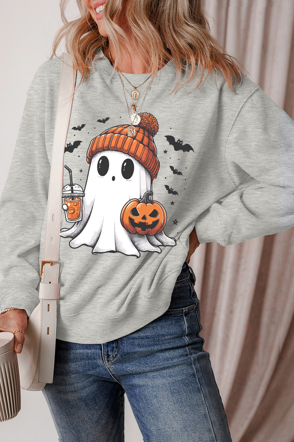 Gray crewneck sweatshirt with a cartoon ghost holding a pumpkin and drink, with bats.