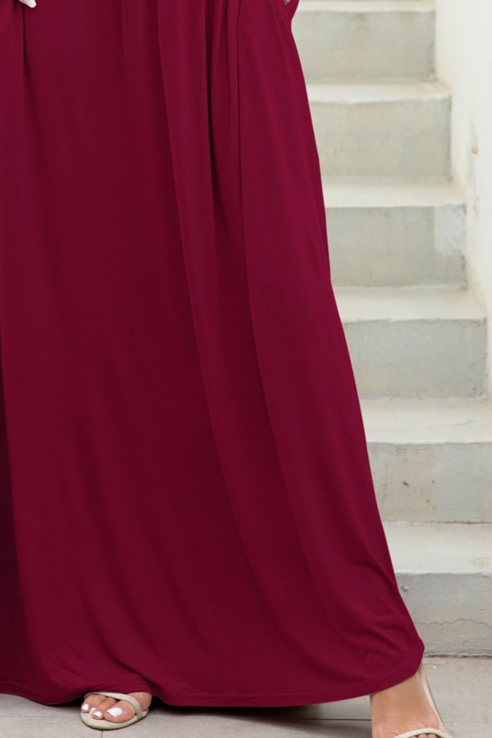 Maxi dress in wine with gathered waist and pockets, shown on stairs.