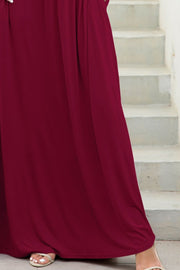 Maxi dress in wine with gathered waist and pockets, shown on stairs.