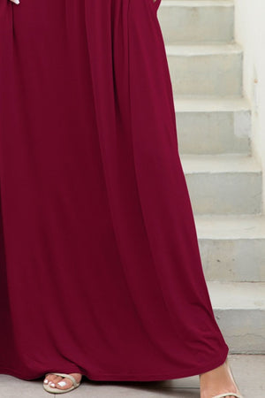 Maxi dress in wine with gathered waist and pockets, shown on stairs.