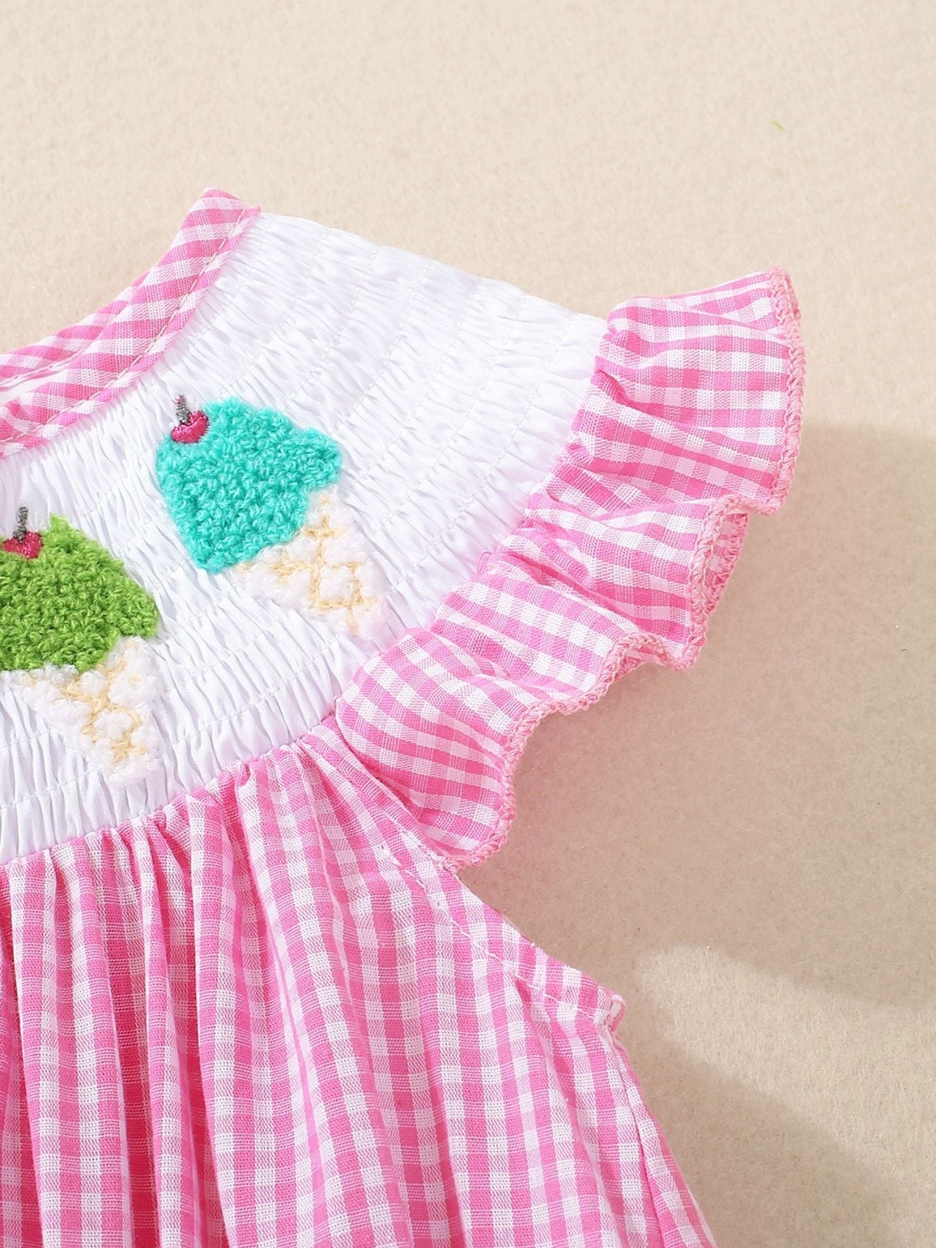 Baby one-piece with pink gingham, smocked white bodice with embroidered ice cream cones and ruffled sleeves.