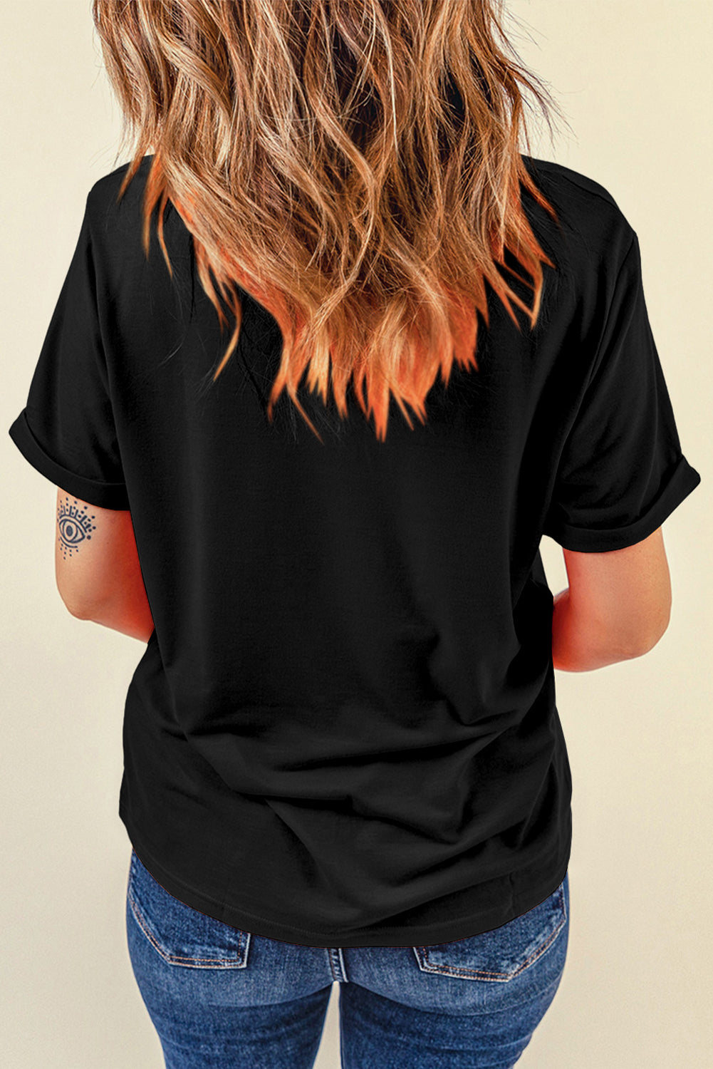 Black cotton-blend tee with cuffed short sleeves and a subtle eye tattoo on the arm.