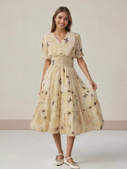 Beige butterfly print midi dress with smocked waist, V-neck, short ruffled sleeves, and tiered skirt.