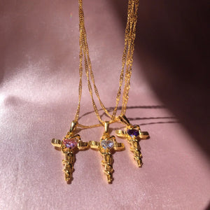 Gold-plated cross charm necklaces with heart-shaped gemstones in pink, clear, and purple.