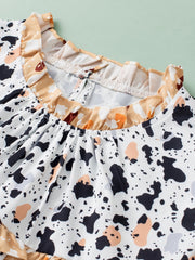 White blouse with terrazzo print, ruffle neckline, and gathered yoke detail.