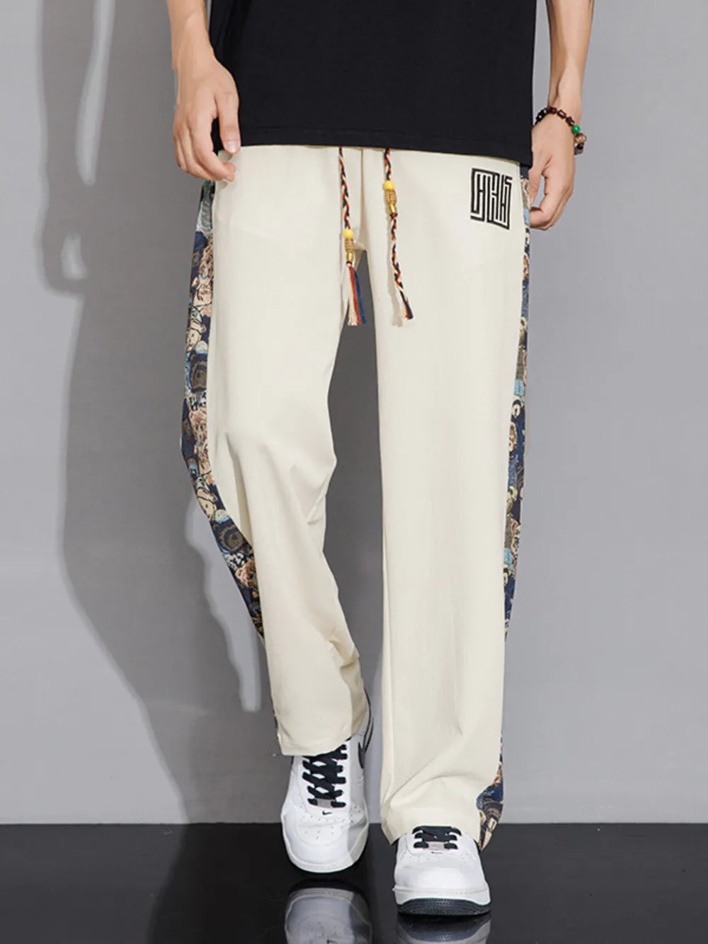 Men's eggshell sweatpants with printed side stripes and drawstring waist.