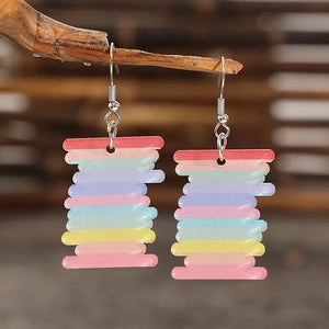 Prismatic spool acrylic earrings in multicolor with rainbow stripes.