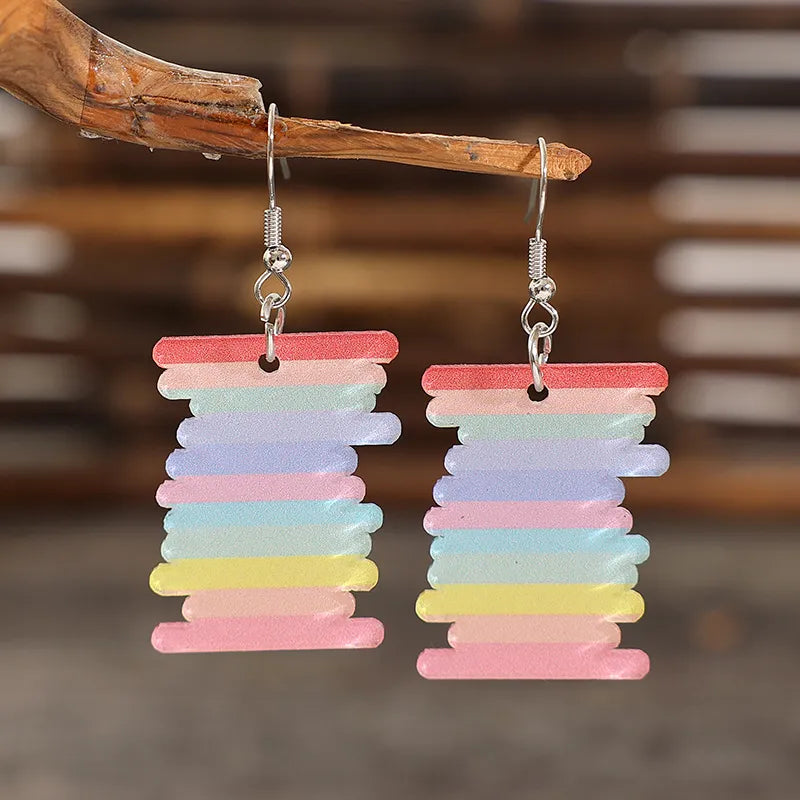 Prismatic spool acrylic earrings in multicolor with rainbow stripes.