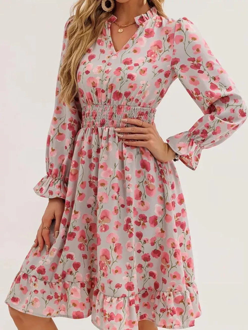 Romantic floral smocked dress in blush pink with V-neck and ruffled hem.