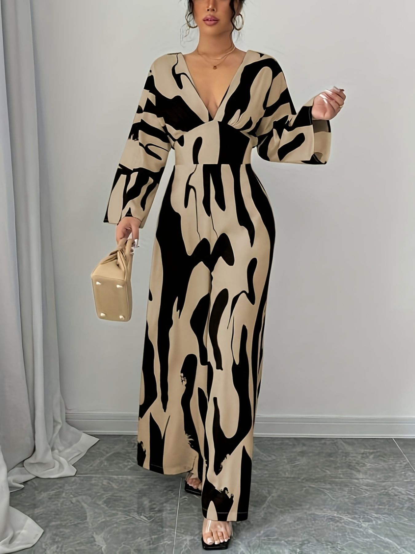 Abstract print wide leg jumpsuit with V-neck and belted waist.