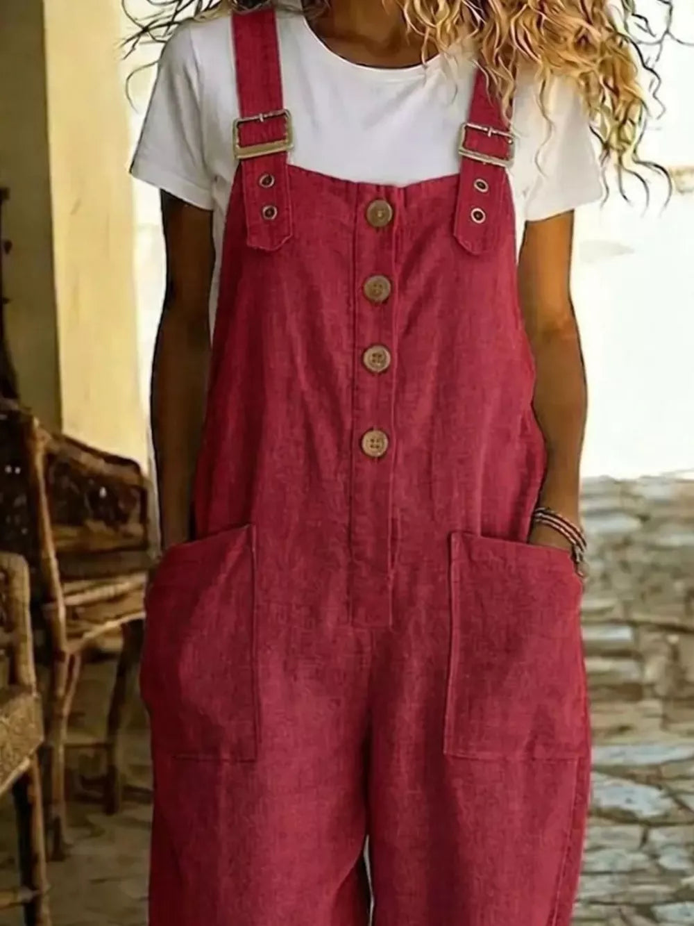 Red button-front wide leg romper with pockets and adjustable buckle straps.