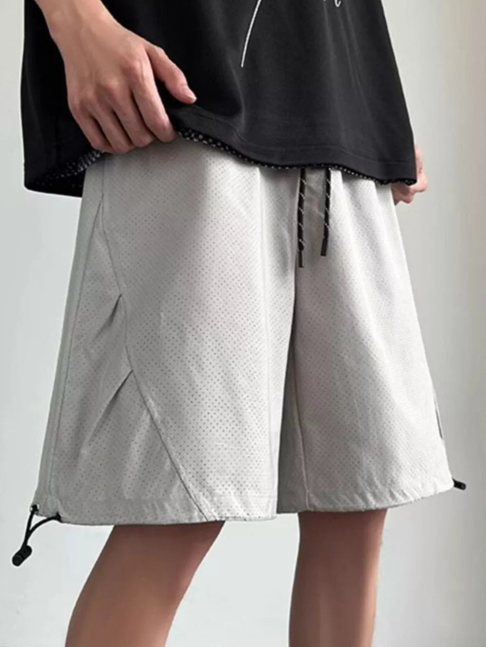 Gray perforated chino shorts with drawstring waist and adjustable hem.