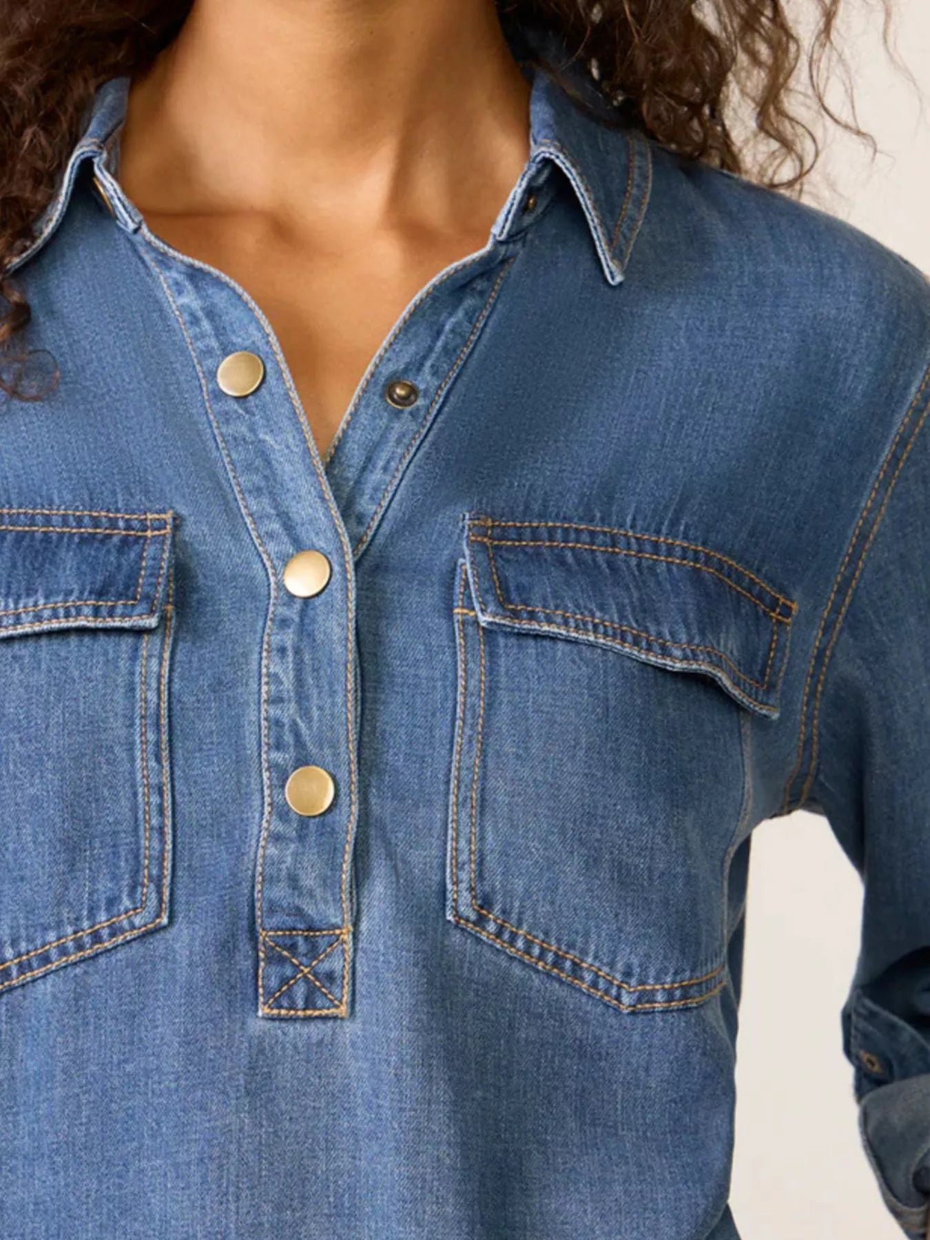 Blue denim cropped half snap shirt with two chest pockets and gold buttons.
