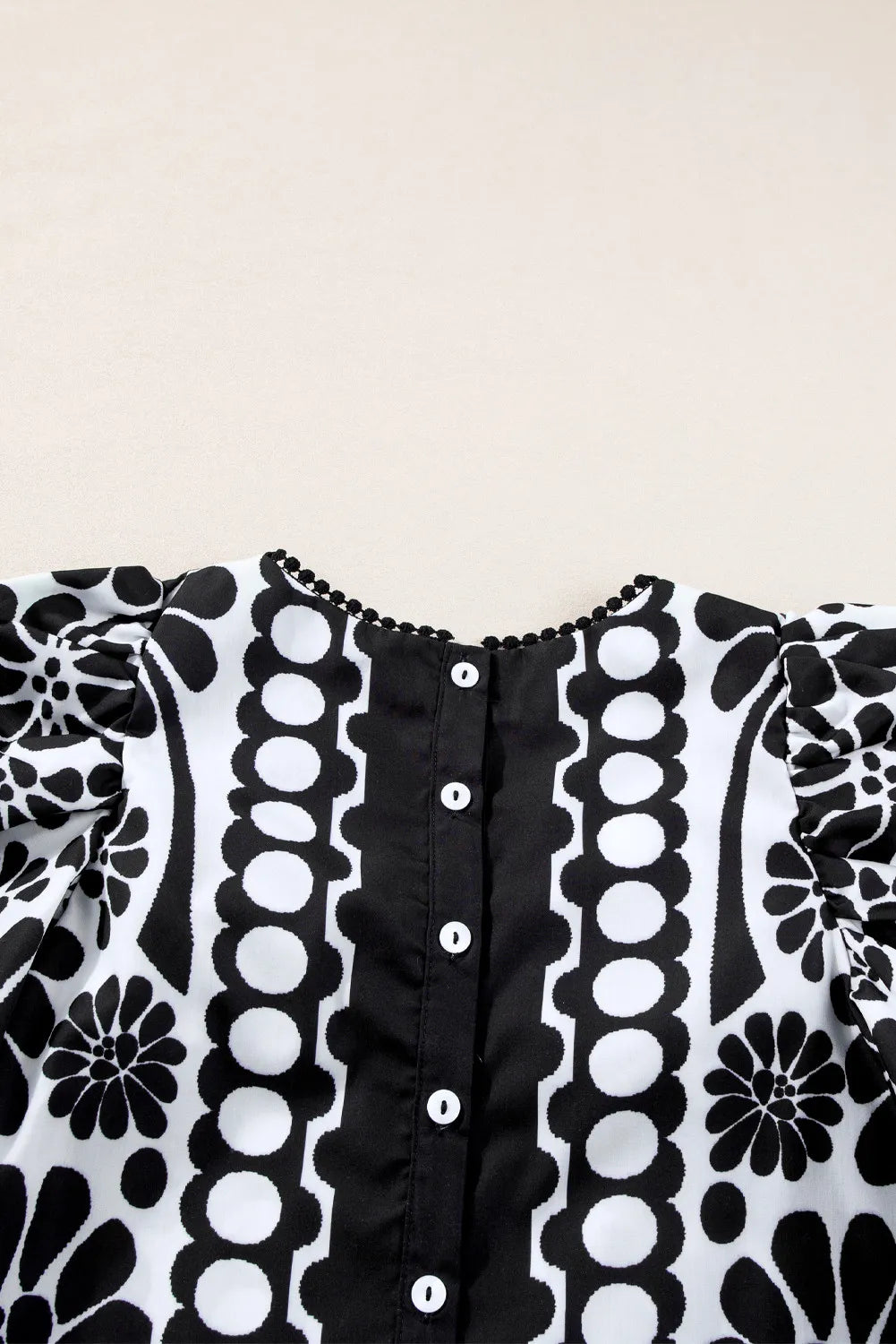 Black floral puff sleeve blouse with button back and pom-pom trim neckline.