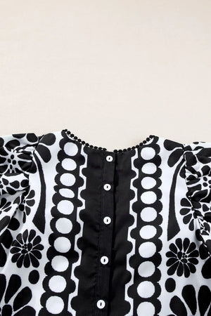 Black floral puff sleeve blouse with button back and pom-pom trim neckline.