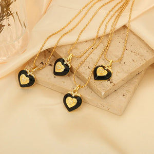 Gold necklace with black enamel heart pendant and diamond accents