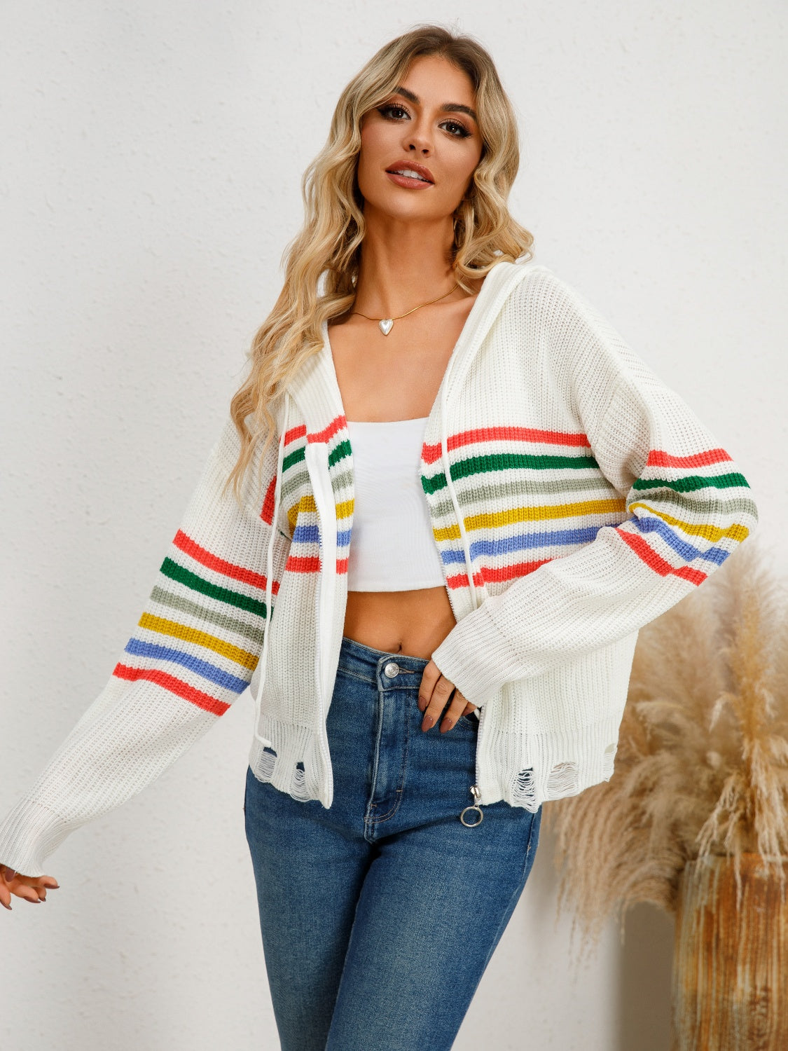 White distressed knit hoodie with rainbow stripes and a drawstring hood.