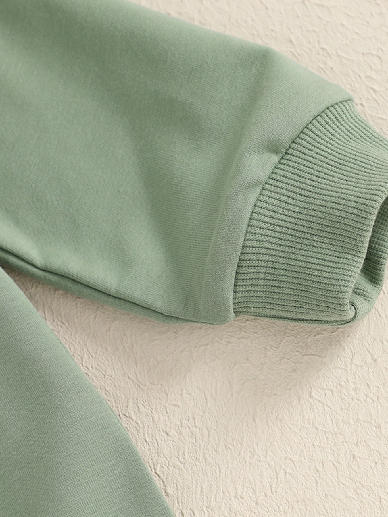 Green cotton baby outfit with ribbed cuffs and applique detail.