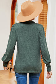 Dark green buttoned blouse with lantern sleeves and gold button detail on cuffs.