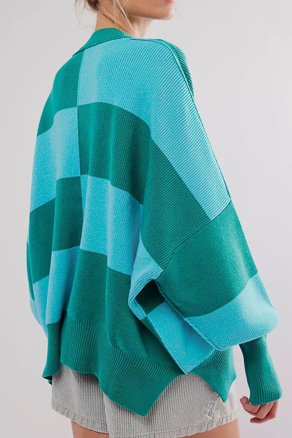 Checkerboard knit oversized sweater in turquoise and green with a collar and wide sleeves.