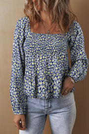 Daisy print smocked peplum blouse in dusty blue with square neckline and long puff sleeves.