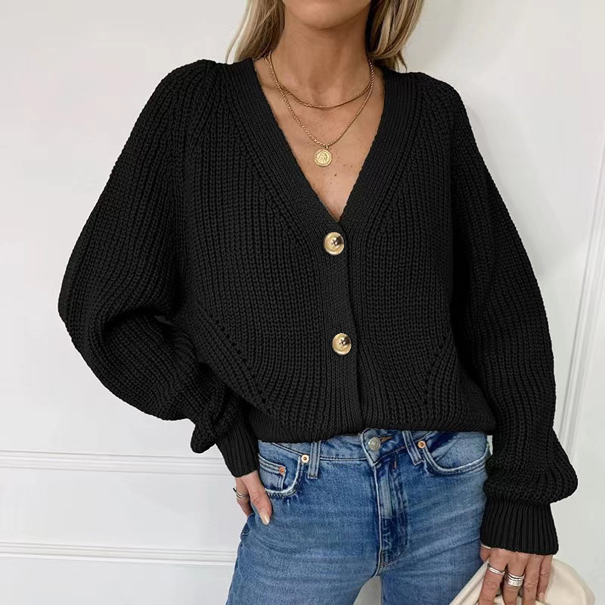 Black ribbed knit cardigan with balloon sleeves and button front, styled with jeans.