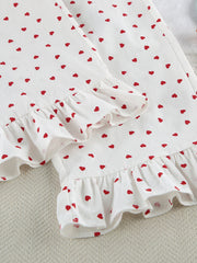 White cotton pajama set with red heart pattern and ruffled trim.