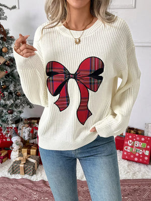 Cream ribbed knit sweater with a red plaid bow detail, crew neck.