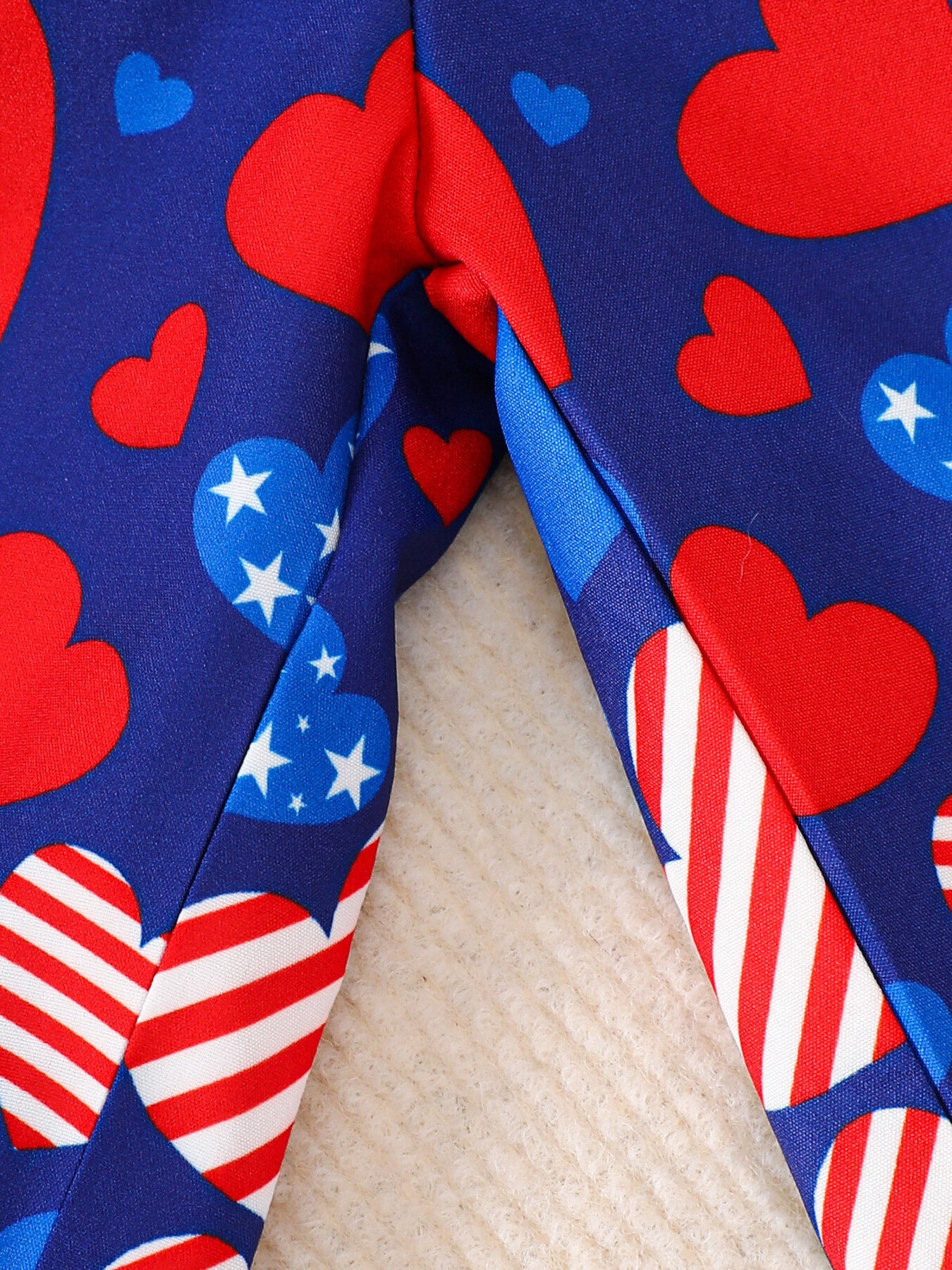 Patriotic baby outfit with red, white, and blue hearts and stripes pattern.