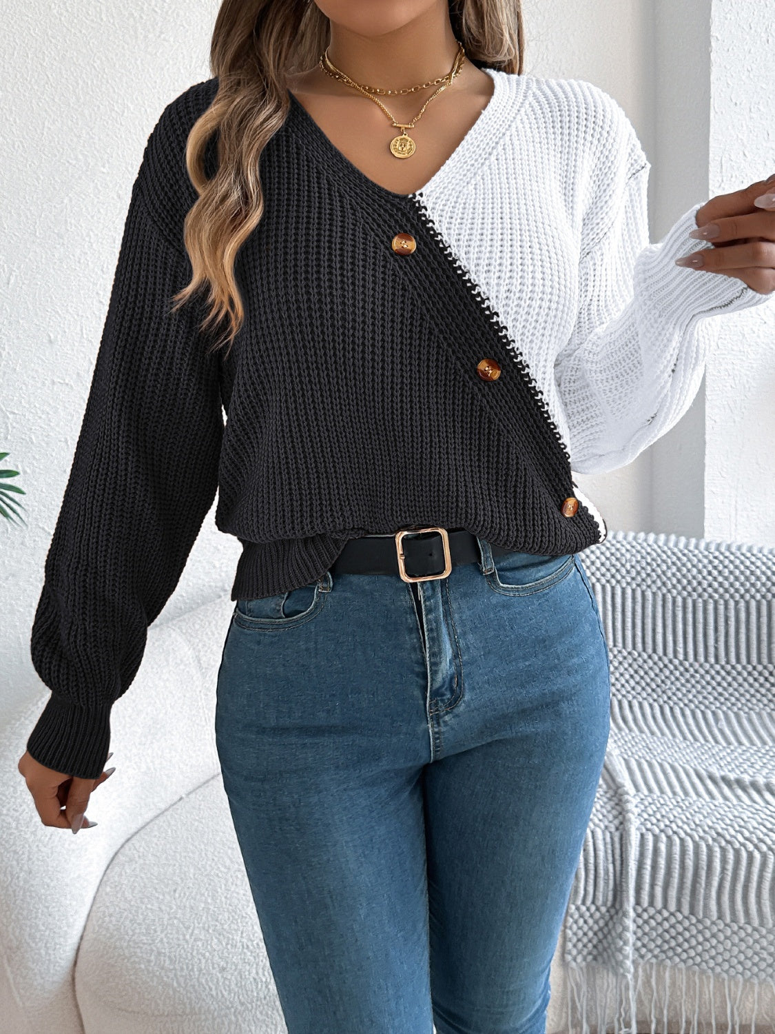 Asymmetrical colorblock knit sweater in black and white with button details.