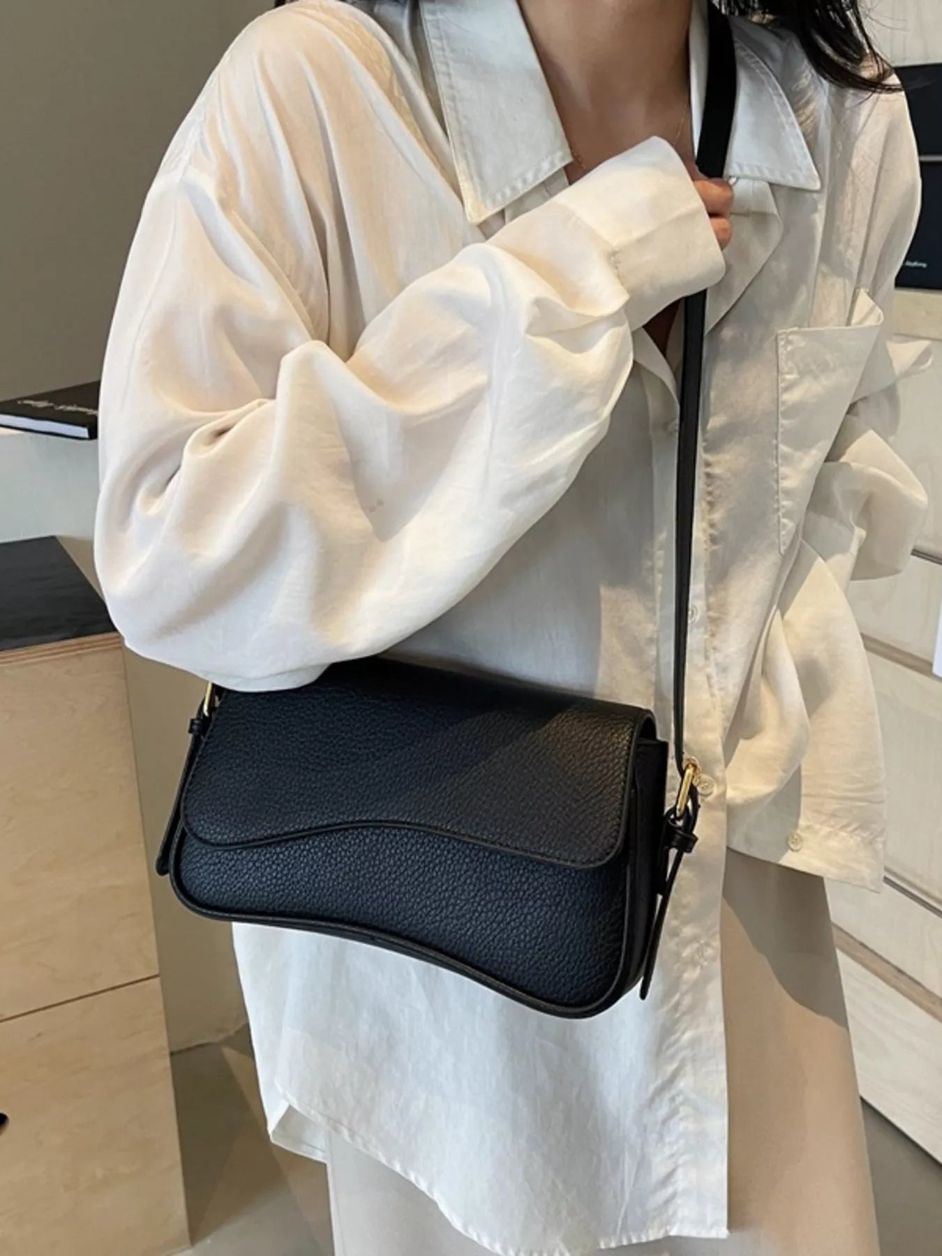Sleek black faux leather crossbody bag with textured flap and gold hardware.