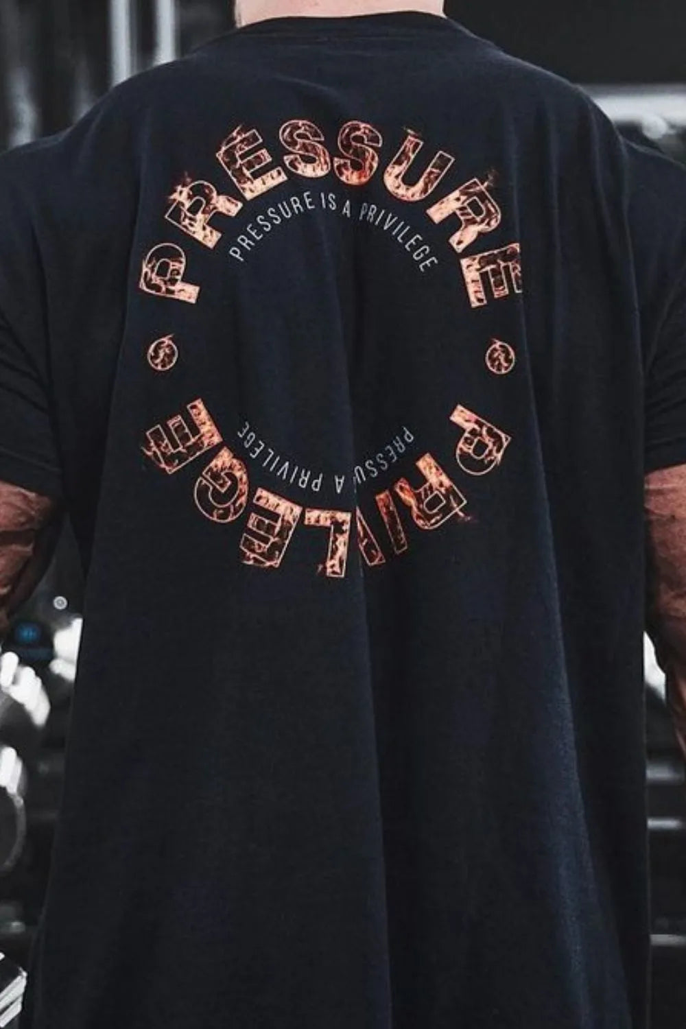 Black graphic t-shirt with circular "Pressure Is A Privilege" text and distressed font detail.