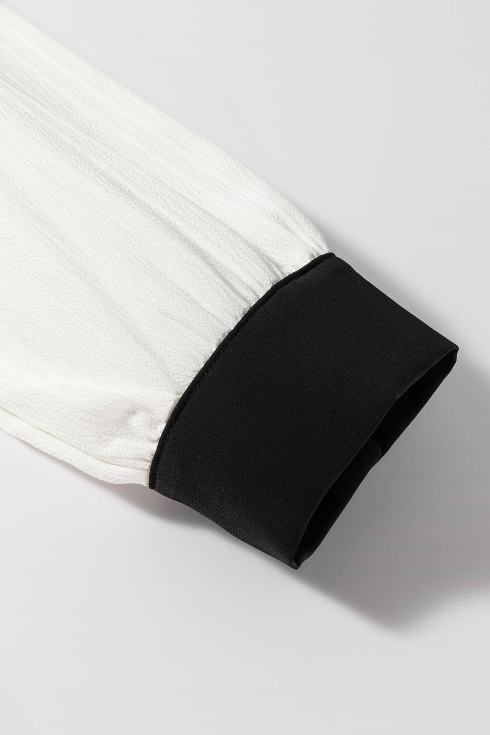 White textured blouse sleeve with black trim cuff