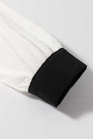 White textured blouse sleeve with black trim cuff