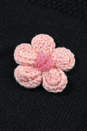 Black knit cardigan with a pink crochet flower applique detail.