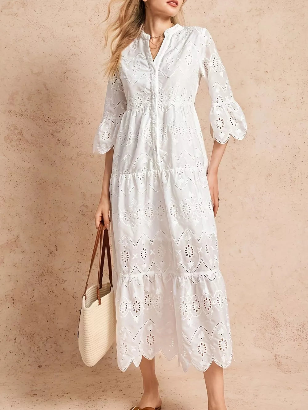 White eyelet midi dress with tiered skirt, button front, and ruffled sleeves.
