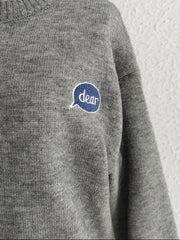 Dark gray acrylic knit sweater with embroidered "dear" speech bubble detail on chest.