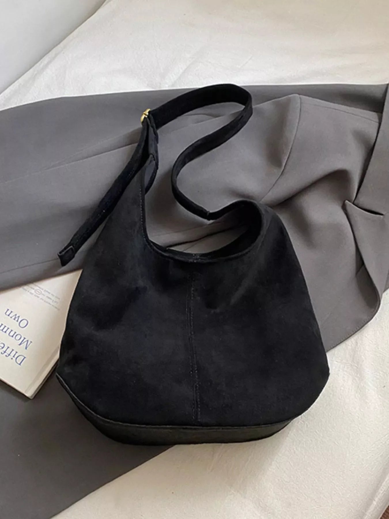 Large black suede hobo shoulder bag with a curved strap and flat base.
