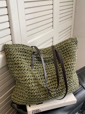 Green woven straw shoulder bag with dark brown leather straps.