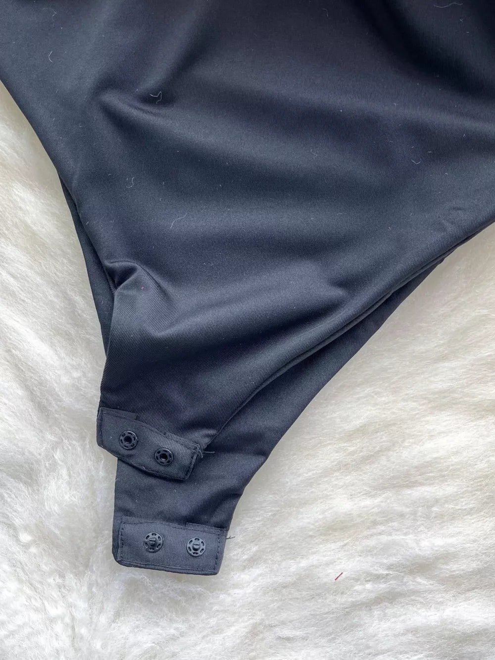 Black ruffled V-neck bodysuit with lace detail and snap closure