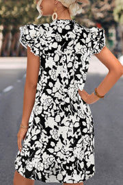 Black floral print trapeze dress with butterfly sleeves and pom-pom trim.