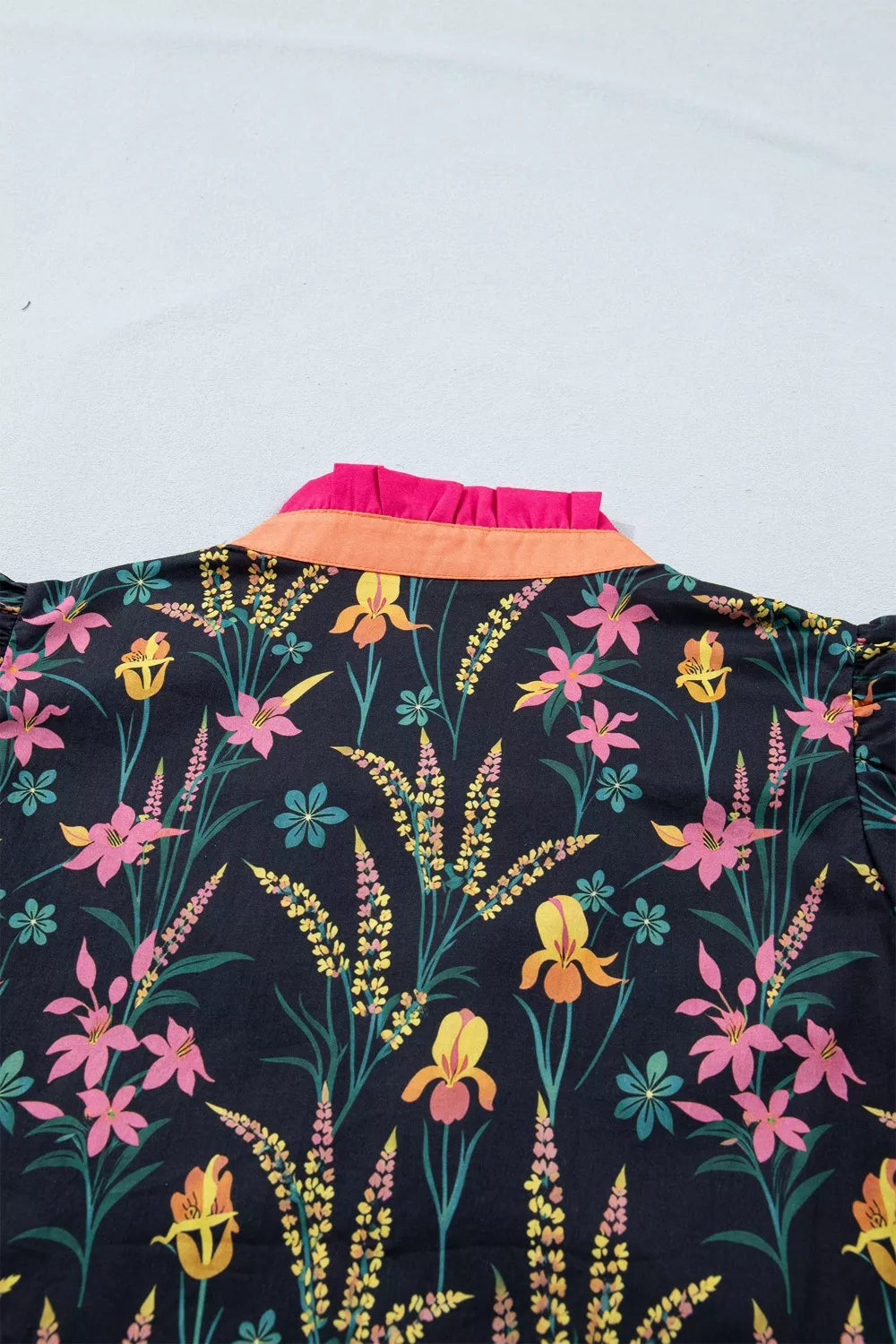 Vibrant floral print cotton blouse with contrast orange and pink ruffled collar.