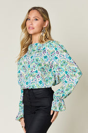 Painterly print blouse in sky blue with gathered long sleeves and a mock neckline.