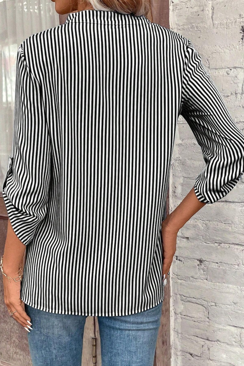 Black and white vertical stripe V-neck blouse with roll-tab sleeves.
