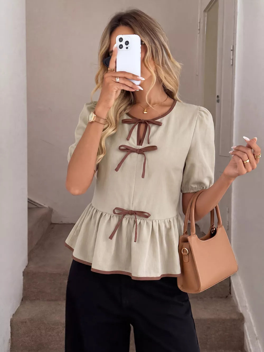 Beige V-neck blouse with brown trim and bow details, short puff sleeves, and ruffle hem.