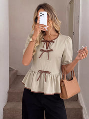 Beige V-neck blouse with brown trim and bow details, short puff sleeves, and ruffle hem.