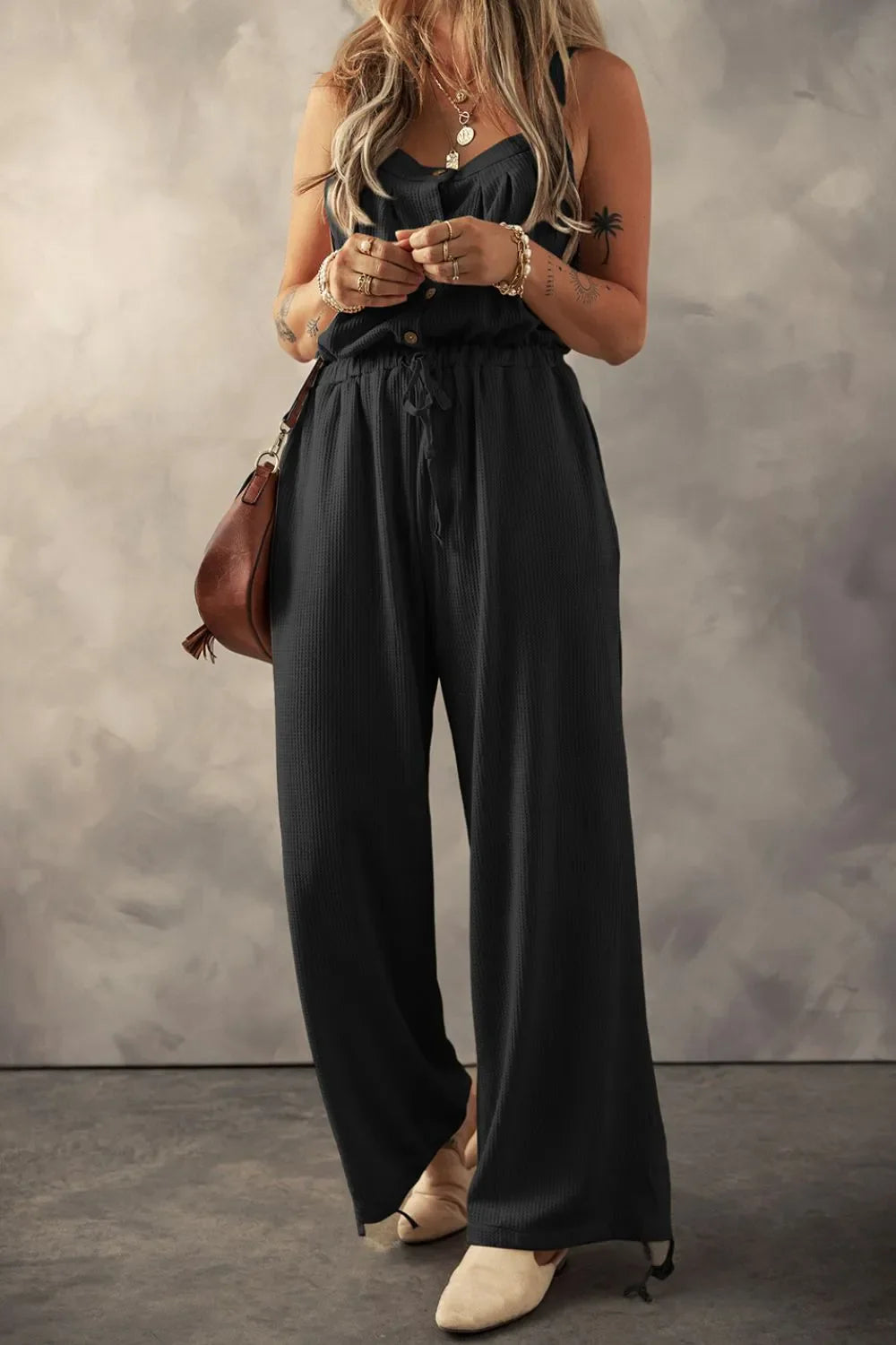 Black waffle knit wide leg jumpsuit with drawstring waist and button front.