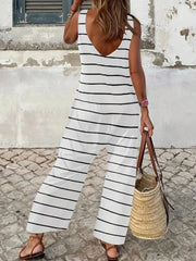 White striped sleeveless wide-leg jumpsuit with a V-neck and straw bag.